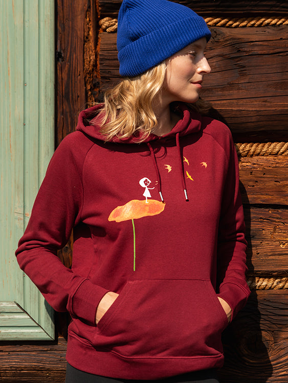 Dunkelroter damen kapuzen-pullover mit Bio-Baumwolle, nachhaltig, fair und vegan produziert. Raglan-Schnitt mit Grafik-Print auf der Vorderseite über der känguru-tasche: Ein Mädchen steht auf einer orangen Blume und es fliegen Vögel davon.