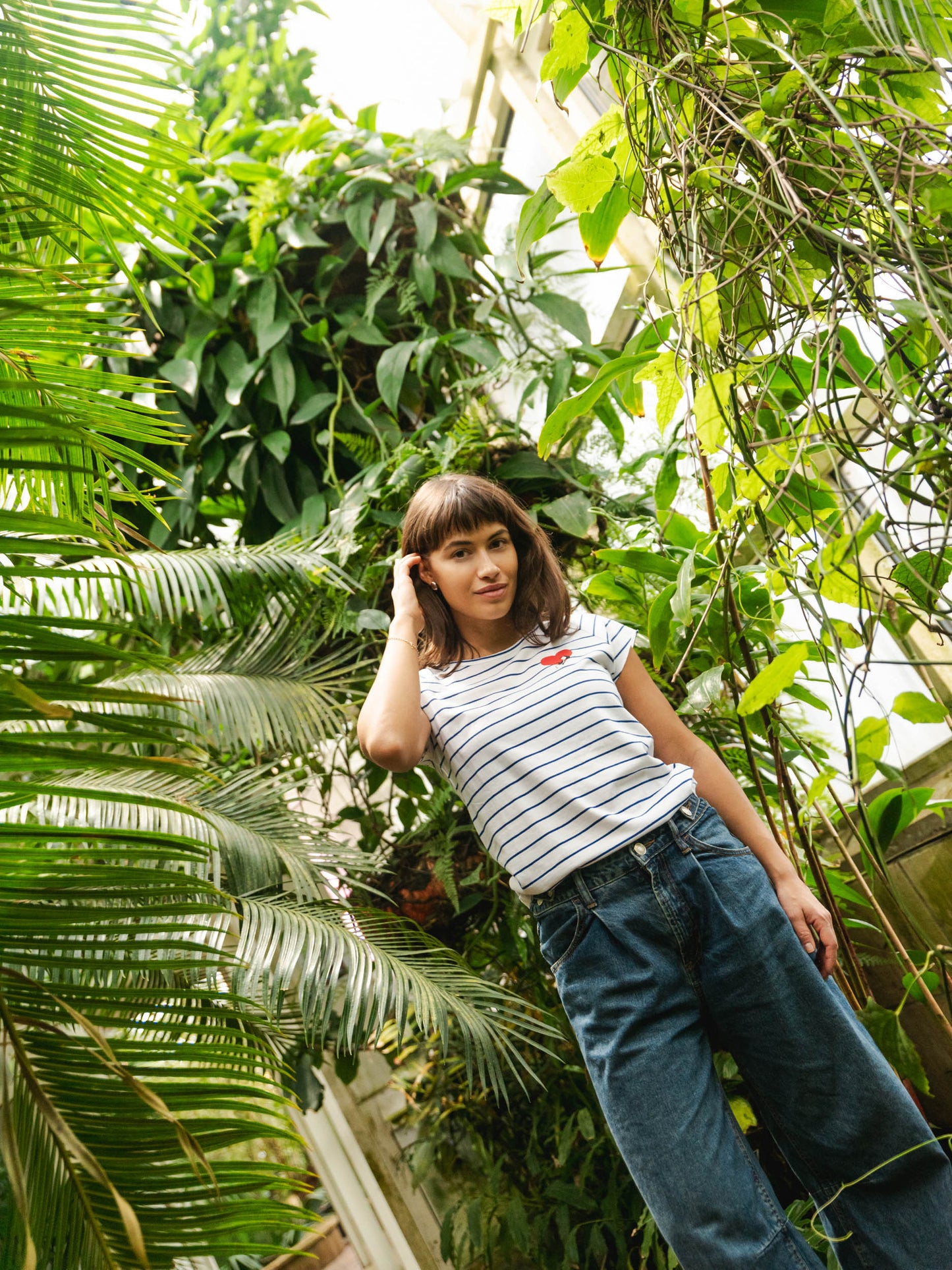 Ein Model trägt ein blau weiß gestreiftes Damen T-Shirt aus Bio-Baumwolle, fair und vegan produziert. Das Raglan-Shirt hat einen Grafik-Print auf der Vorderseite: Ein Herz in dem ein kleines Mädche sitzt. Der Druck ist mit wasserbasierenden Farben ohne Schadstoffe gedruckt.