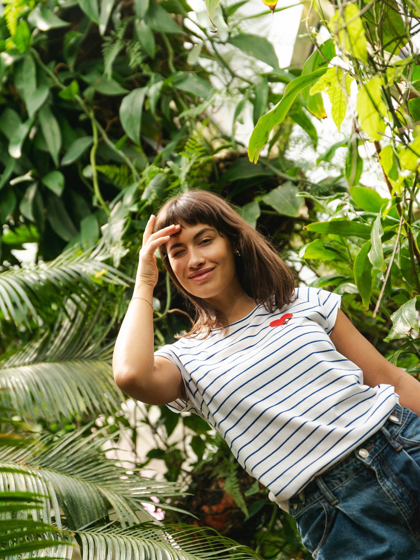 Ein Model trägt ein blau weiß gestreiftes Damen T-Shirt aus Bio-Baumwolle, fair und vegan produziert. Das Raglan-Shirt hat einen Grafik-Print auf der Vorderseite: Ein Herz in dem ein kleines Mädche sitzt. Der Druck ist mit wasserbasierenden Farben ohne Schadstoffe gedruckt.