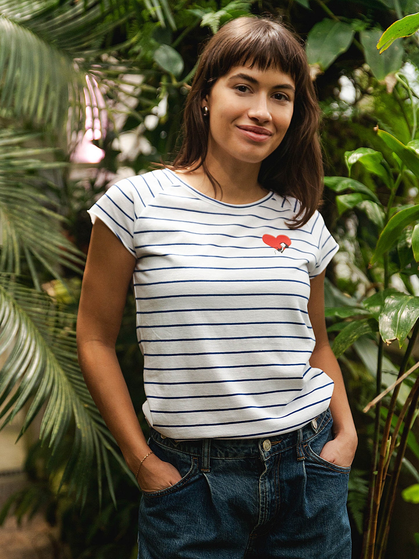 Ein Model trägt ein blau weiß gestreiftes Damen T-Shirt aus Bio-Baumwolle, fair und vegan produziert. Das Raglan-Shirt hat einen Grafik-Print auf der Vorderseite: Ein Herz in dem ein kleines Mädche sitzt. Der Druck ist mit wasserbasierenden Farben ohne Schadstoffe gedruckt.