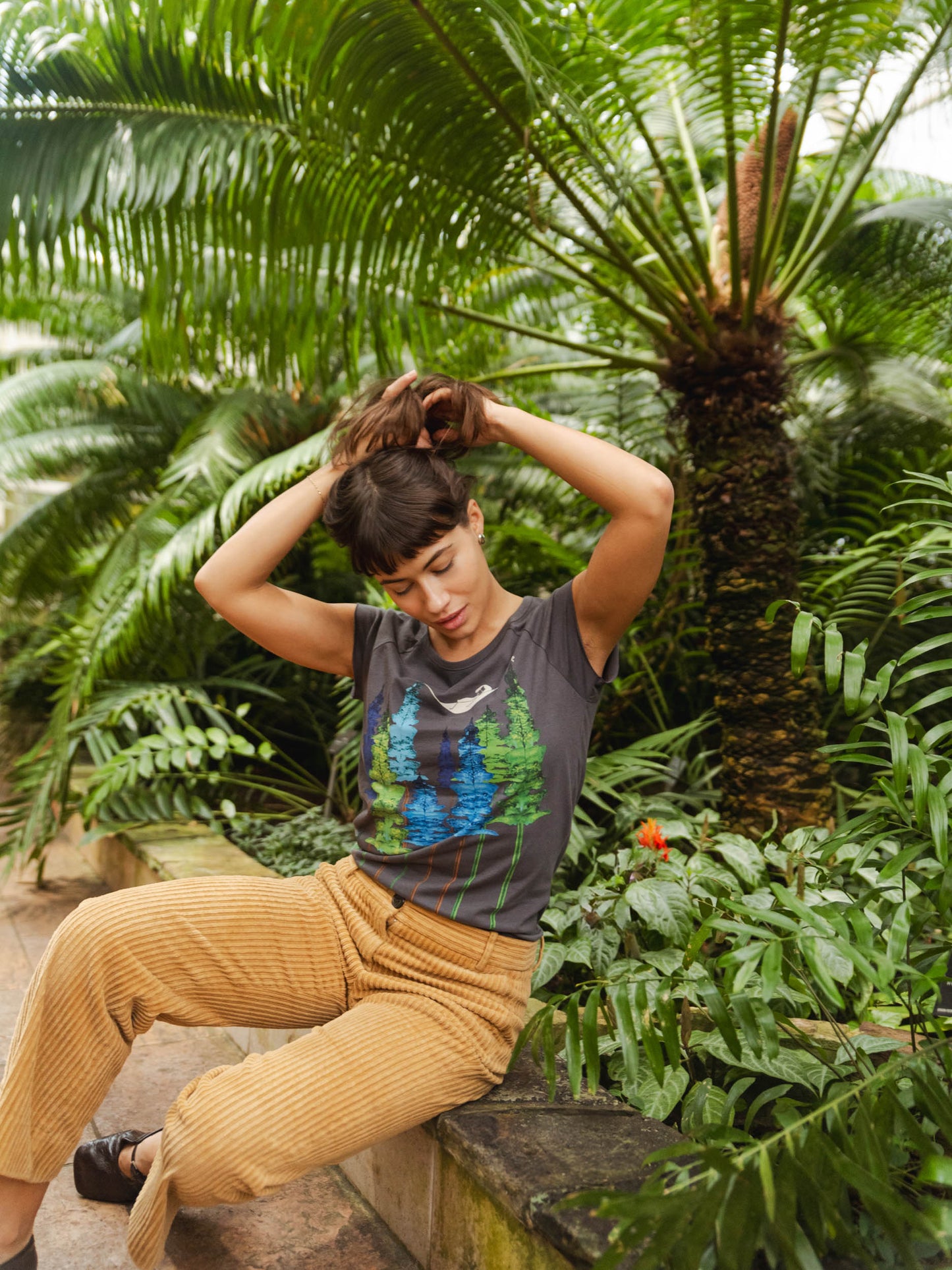 Dunkel-graues Damen T-Shirt aus Bio-Baumwolle, fair und vegan produziert. Raglan-Shirt mit Grafik-Print auf der Vorderseite: Ein Mädchen liegt in einer hängematte, die in den Wipfeln eines Waldes hängt.