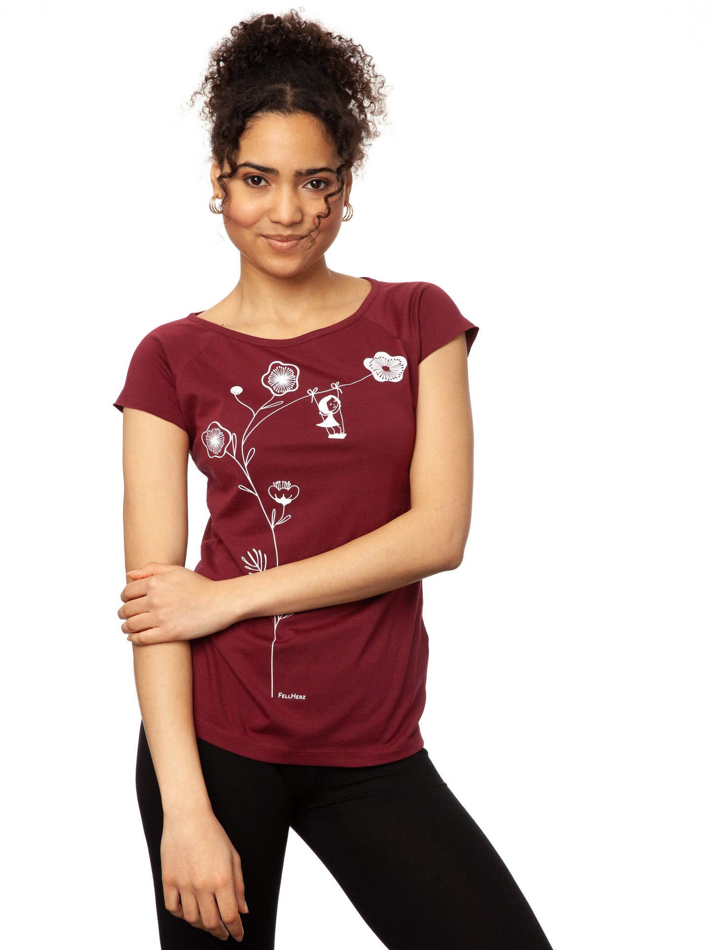 Ein Damen-T-Shirt in kräftigem Rubinrot mit kurzen Cap-Ärmeln. Auf der Vorderseite ist ein filigranes Siebdruck-Motiv eines Mädchens auf einer Schaukel zu sehen, die an einem Kirschblüten Zweig hängt. Das T-Shirt hat eine leicht taillierte Passform und besteht aus weicher Bio-Baumwolle und ist nachhaltig und fair produziert.