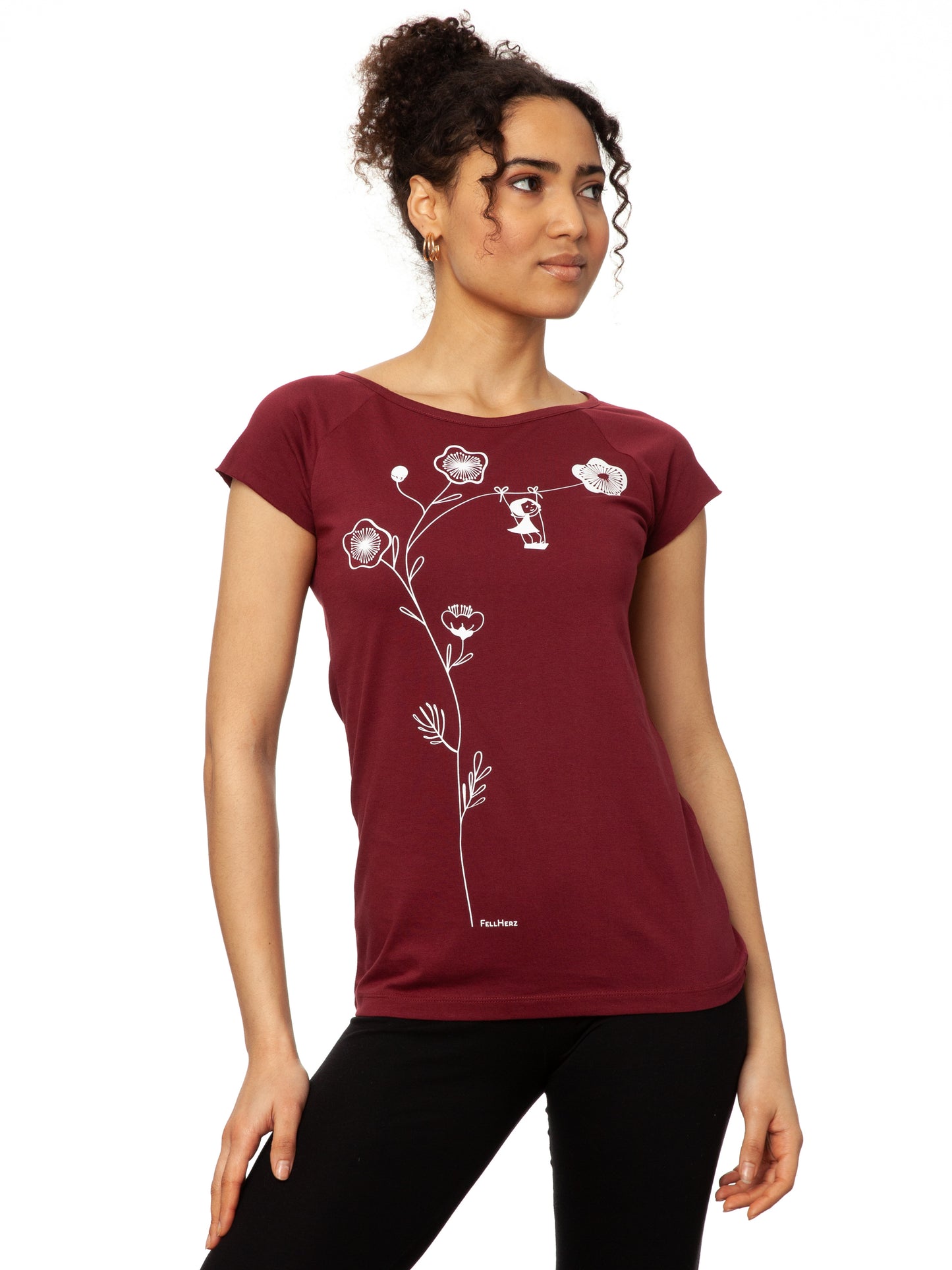 Ein Damen-T-Shirt in kräftigem Rubinrot mit kurzen Cap-Ärmeln. Auf der Vorderseite ist ein filigranes Siebdruck-Motiv eines Mädchens auf einer Schaukel zu sehen, die an einem Kirschblüten Zweig hängt. Das T-Shirt hat eine leicht taillierte Passform und besteht aus weicher Bio-Baumwolle und ist nachhaltig und fair produziert.