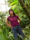 Lila Frauen Yoga T-Shirt mit Asana-Girl-Print auf der Brust: ein brauner Ast mit pinken Beeren, auf denen ein kleines Mädchen in Balance-Yogapose steht -nachhaltig produziert aus Bio-Baumwolle – modernes Cap Sleeve Shirt für Yoga, Freizeit und Meditation.