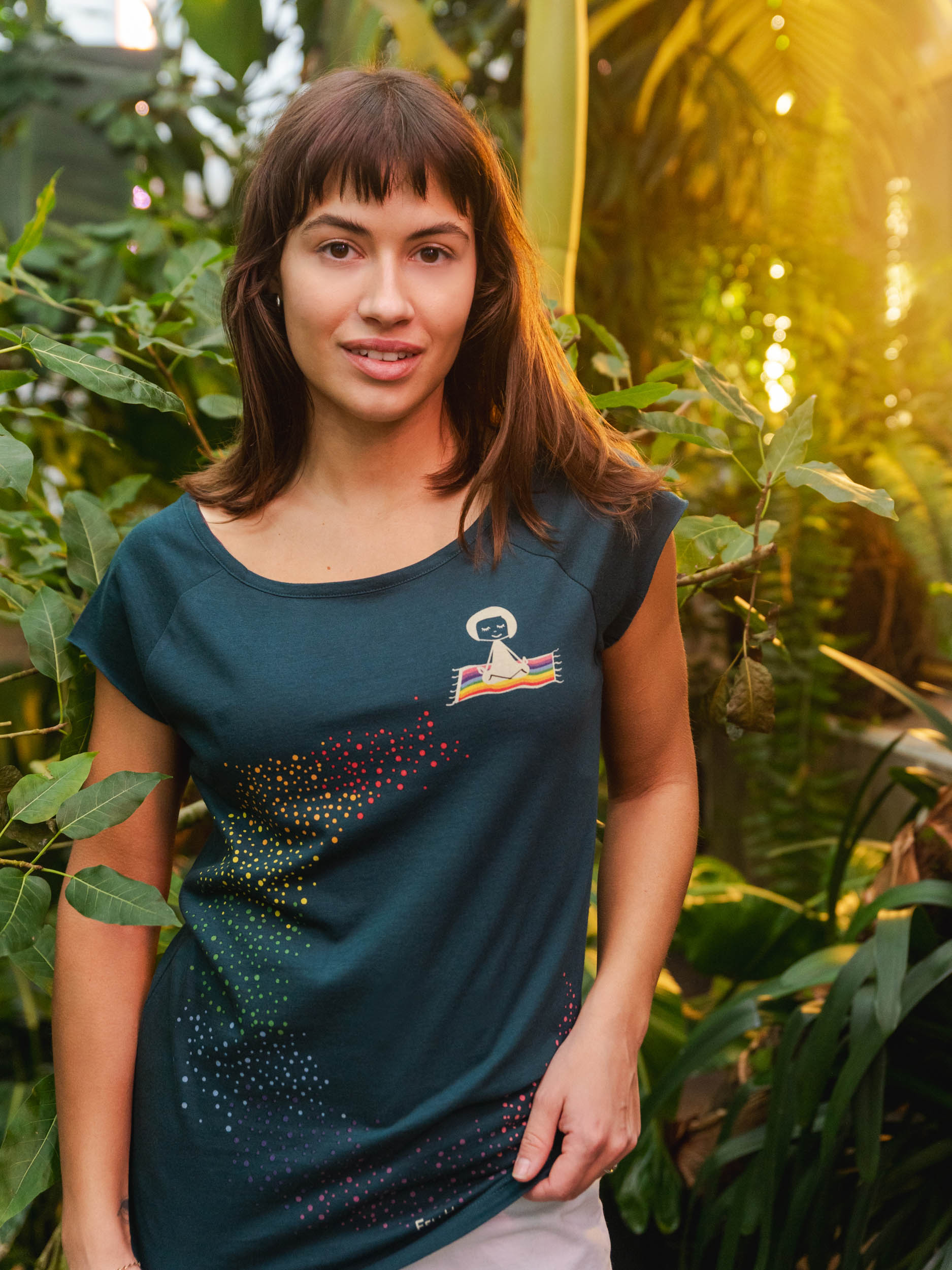 Damen‑Cap‑Sleeve‑T‑Shirt in tiefem Deep Teal, 100 % weiche GOTS‑zertifizierte Bio‑Baumwolle mit modernem, leicht tailliertem Schnitt und digitalem FellHerz‑Print mit einem kleinen Mädchen, dass auf einem regenbogenfarbenen fliegenden Teppich sitzt und einen regenbogenen Schweif hinter sich her zieht – nachhaltig, fair produziert, ideal für warme Tage oder als Lagen‑Basic.