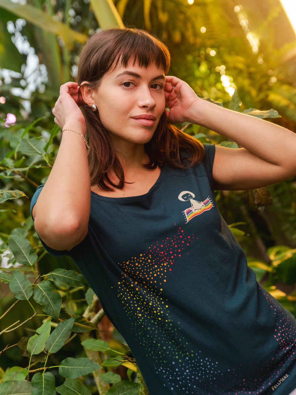 Damen‑Cap‑Sleeve‑T‑Shirt in tiefem Deep Teal, 100 % weiche GOTS‑zertifizierte Bio‑Baumwolle mit modernem, leicht tailliertem Schnitt und digitalem FellHerz‑Print mit einem kleinen Mädchen, dass auf einem regenbogenfarbenen fliegenden Teppich sitzt und einen regenbogenen Schweif hinter sich her zieht – nachhaltig, fair produziert, ideal für warme Tage oder als Lagen‑Basic.