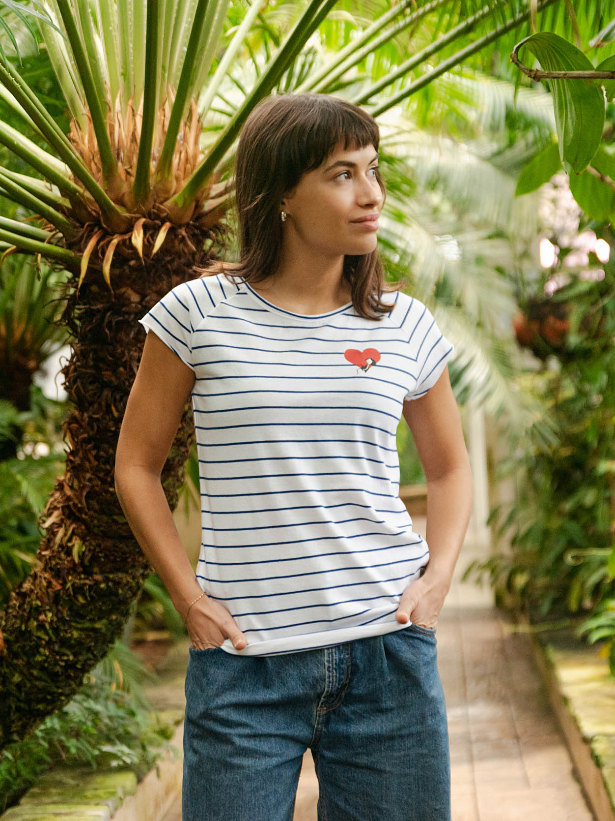 Ein Model trägt ein blau weiß gestreiftes Damen T-Shirt aus Bio-Baumwolle, fair und vegan produziert. Das Raglan-Shirt hat einen Grafik-Print auf der Vorderseite: Ein Herz in dem ein kleines Mädche sitzt. Der Druck ist mit wasserbasierenden Farben ohne Schadstoffe gedruckt.