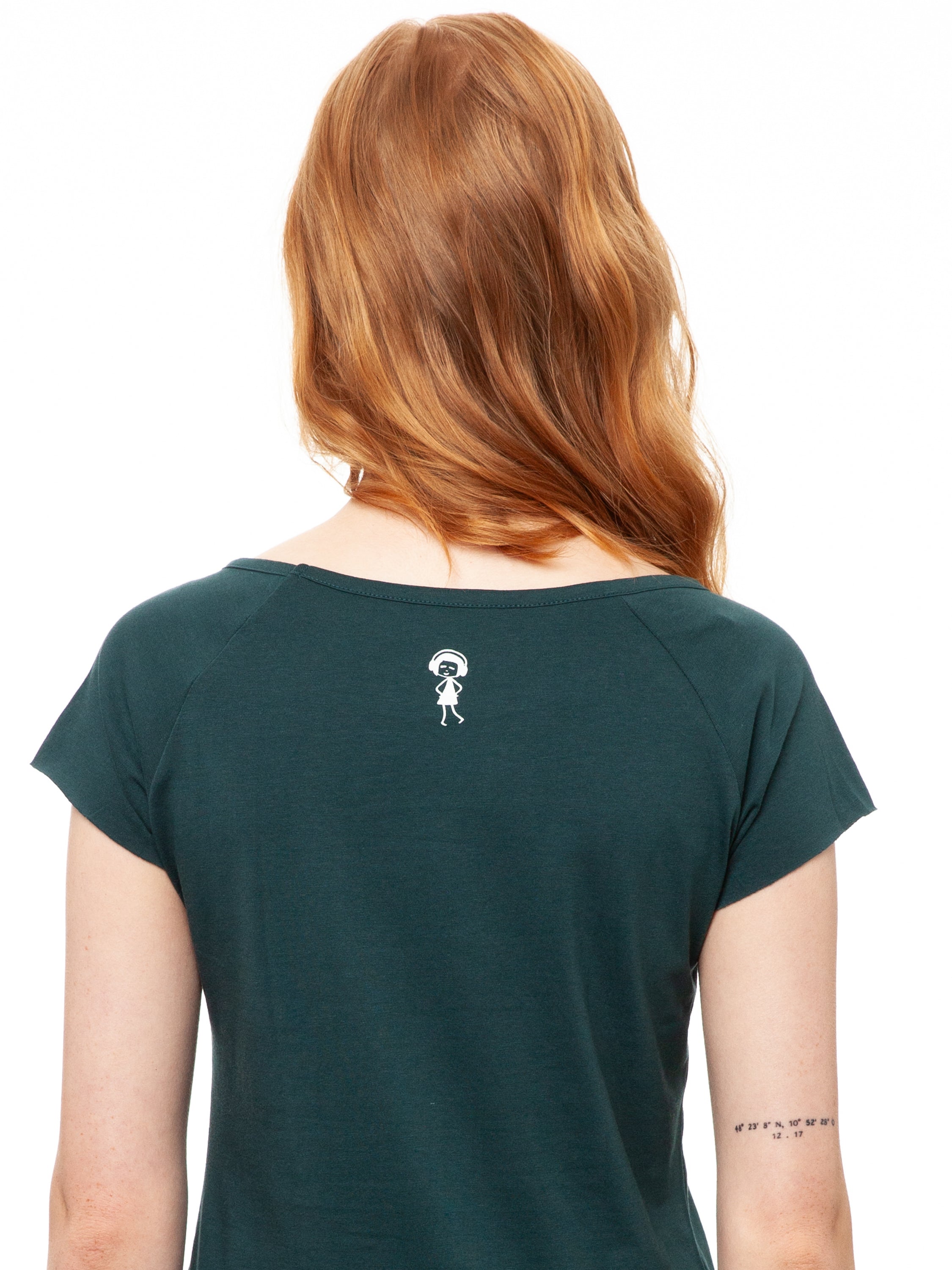 Ein Model trägt ein petrolfarbens Damen T‑Shirt aus 100 % Bio‑Baumwolle mit kurzen Cap‑Sleeves, maritimem Anker‑Siebdruck vorne und kleinem Logo‑Print auf dem Rücken – nachhaltig, fair produziert und lässig geschnitten