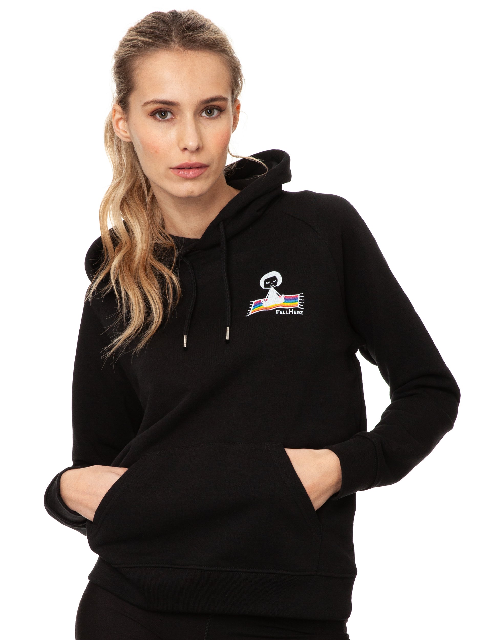 Schwarzer Ommm‑Hoodie aus 85 % Bio‑Baumwolle und 15 % recyceltem Polyester im lässigen Raglan‑Schnitt, mit doppellagiger Kapuze und Ton‑in‑Ton‑Kordel, kuscheliger Kängurutasche und zarter FellHerz‑Illustration eines kleinen Mädchens, das auf einem regenbogenfarbenen Teppich fliegt, im Digitaldruck mit wasserbasierten Farben – nachhaltig, fair produziert und ideal für kalte Tage.