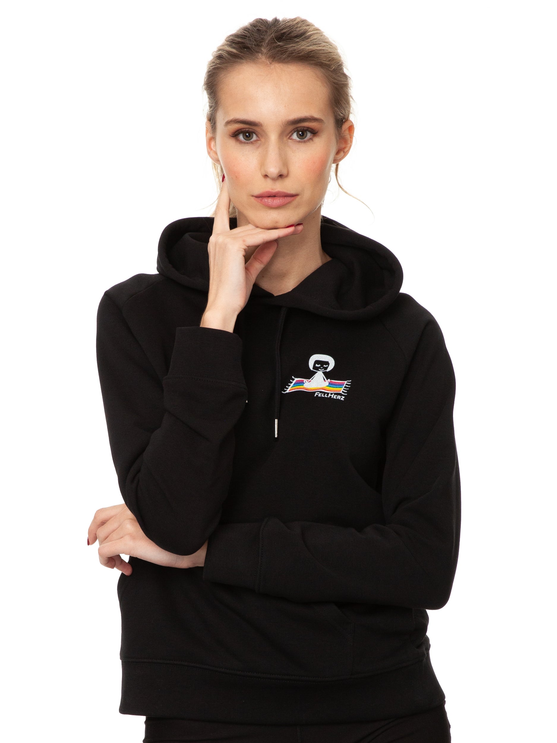 Schwarzer Ommm‑Hoodie aus 85 % Bio‑Baumwolle und 15 % recyceltem Polyester im lässigen Raglan‑Schnitt, mit doppellagiger Kapuze und Ton‑in‑Ton‑Kordel, kuscheliger Kängurutasche und zarter FellHerz‑Illustration eines kleinen Mädchens, das auf einem regenbogenfarbenen Teppich fliegt, im Digitaldruck mit wasserbasierten Farben – nachhaltig, fair produziert und ideal für kalte Tage.