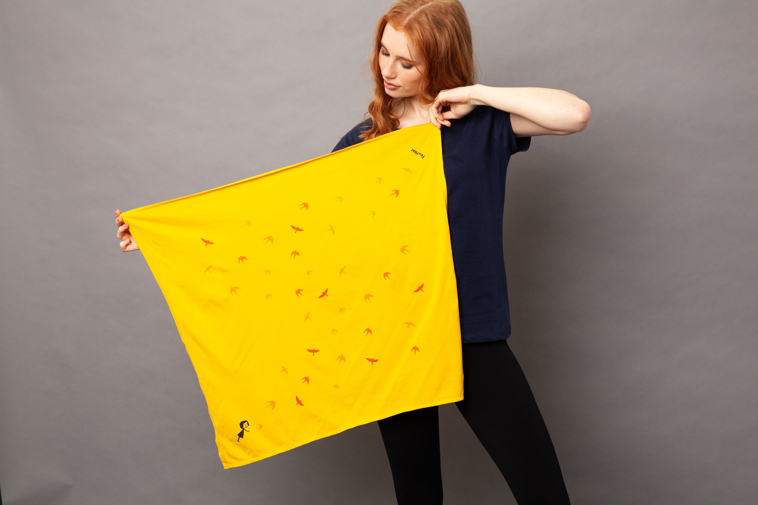 gelbes nachhaltiges FellHerz Furoshiki aus Bio-Baumwolle, fair und vegan produziert mit Schwalbenzug Grafik-Print: Ein kleines Mädchen steht im unteren Eck und es fliegen Vögel davon.