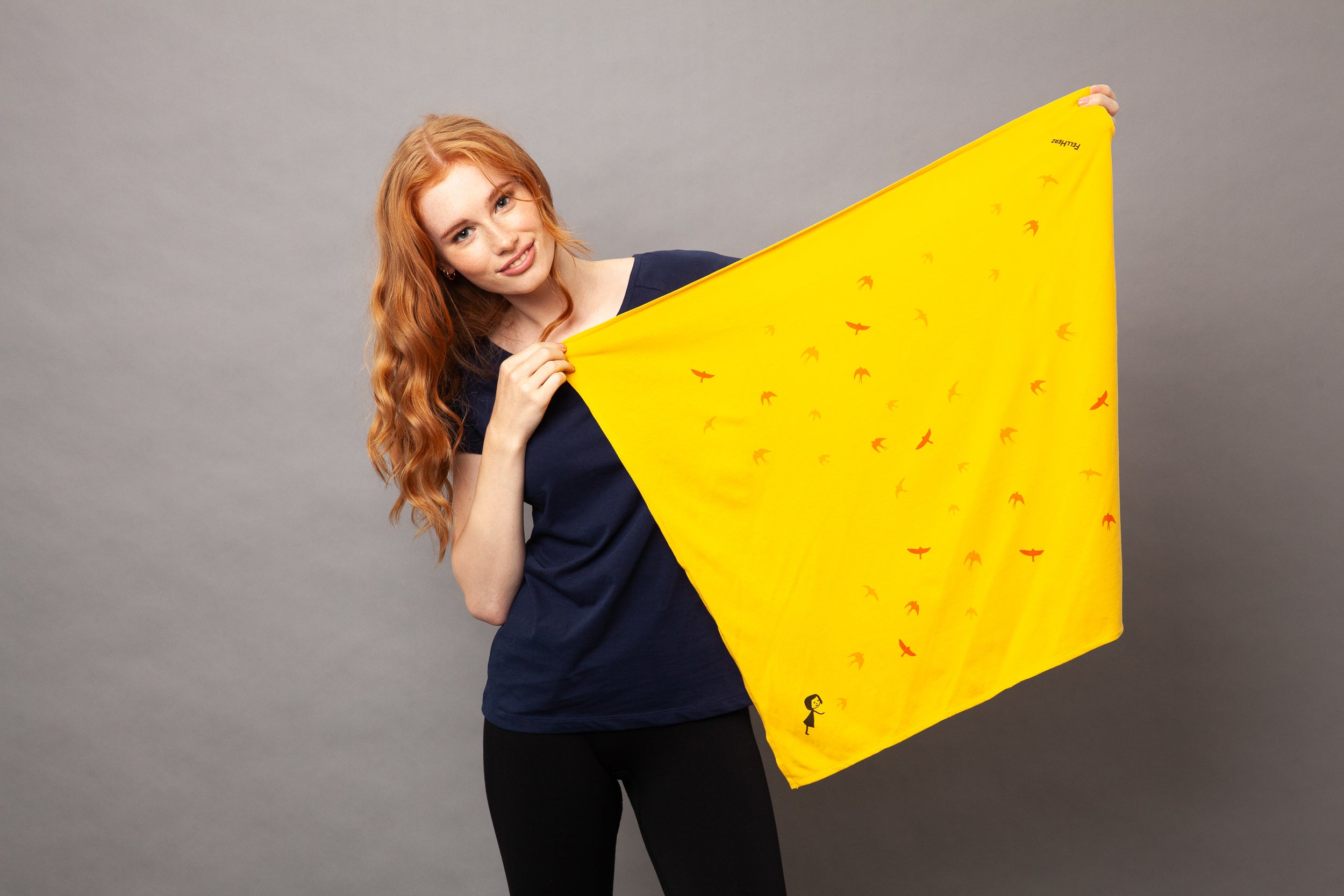 gelbes nachhaltiges FellHerz Furoshiki aus Bio-Baumwolle, fair und vegan produziert mit Schwalbenzug Grafik-Print: Ein kleines Mädchen steht im unteren Eck und es fliegen Vögel davon.