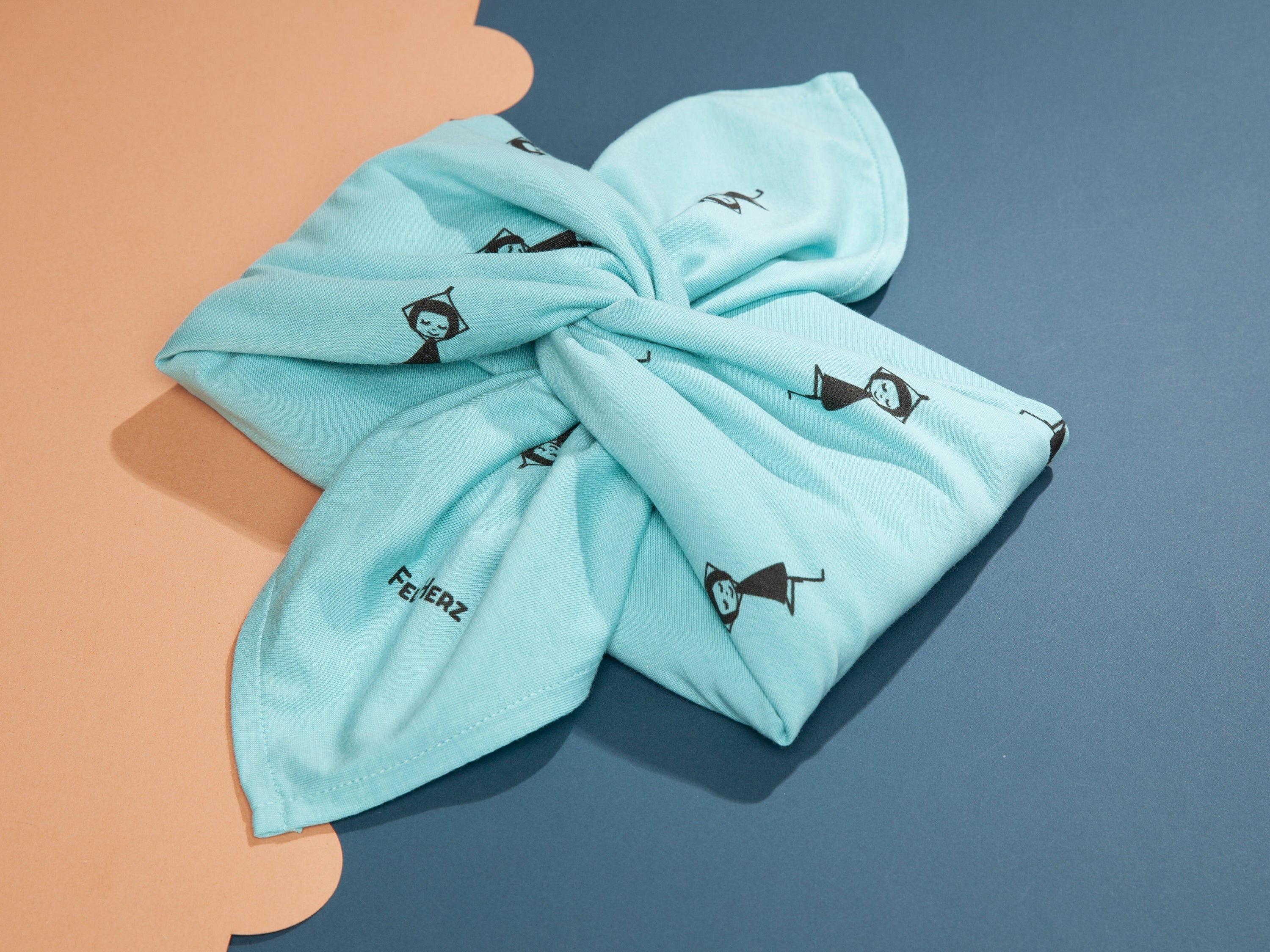 Quadratisches Furoshiki‑Tuch ‘Yogamädchen’ in zartem Neptun‑Mint, ca. 60×60 cm, aus 100 % GOTS‑zertifizierter Bio‑Baumwolle (Upcycling‑Reststoffe), mit vielen kleinen schwarzen Mädchen, die in Yogapose stehen – nachhaltige, faire Geschenk‑Verpackung & vielseitiges Alltagsaccessoire.