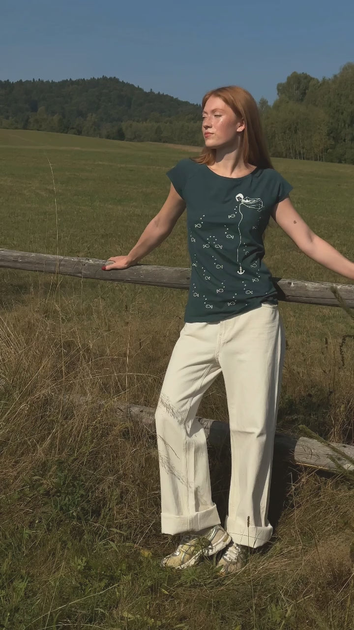 video von einem Model, es trägt ein Damen T‑Shirt deep teal aus 100 % Bio‑Baumwolle mit kurzen Cap‑Sleeves, maritimem Anker‑Siebdruck vorne und kleinem Logo‑Print auf dem Rücken – nachhaltig, fair produziert und lässig geschnitten