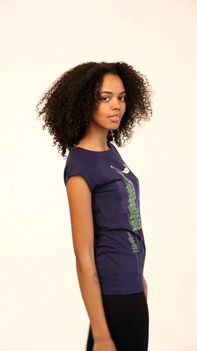 Video mit einem Model, das ein FellHerz Shirt trägt. Dunkelblaues Damen T-Shirt aus Bio-Baumwolle, fair und vegan produziert. Raglan-Shirt mit Grafik-Print auf der Vorderseite: Ein Mädchen liegt in einer Hängematte, die in Baum Wipfeln eines Waldes hängt.