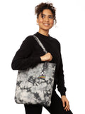 Schwarz weiße Batik‑Tote‑Bag ‘Ommm’ in handgefärbtem Tie‑Dye‑Muster, ca. 37 × 39 cm, aus 300 g/m² Canvas (80 % recycelte Baumwolle, 20 % recycelter Polyester), mit robust verstärkten Kanten, extra Volumen durch Bodennaht und digitalem Ommm‑Print, auf dem ein Mädchen auf einem regenbogenfarbenen Teppich fliegt – fair produziert (Fair Wear), vorgewaschen, waschbar bei 30 °C