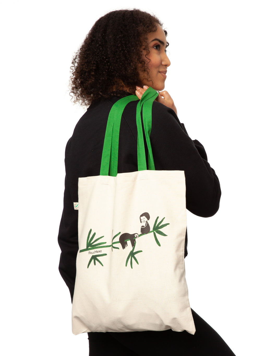 Tasche aus hochwertiger Bio-Baumwolle in Naturweiß mit grünen Henkeln mit einzigartigen FellHerz Faultier-Design in Grün auf der Vorderseite. Die liebevolle Illustration zeigt ein entspanntes Faultier, das sich an einem Zweig festhält, während ein kleines Mädchen daneben sitzt. Diese nachhaltige Bag ist ideal für umweltbewusste Modefans und Fair Fashion Liebhaberinnen und ist ein tolles Accessoire.