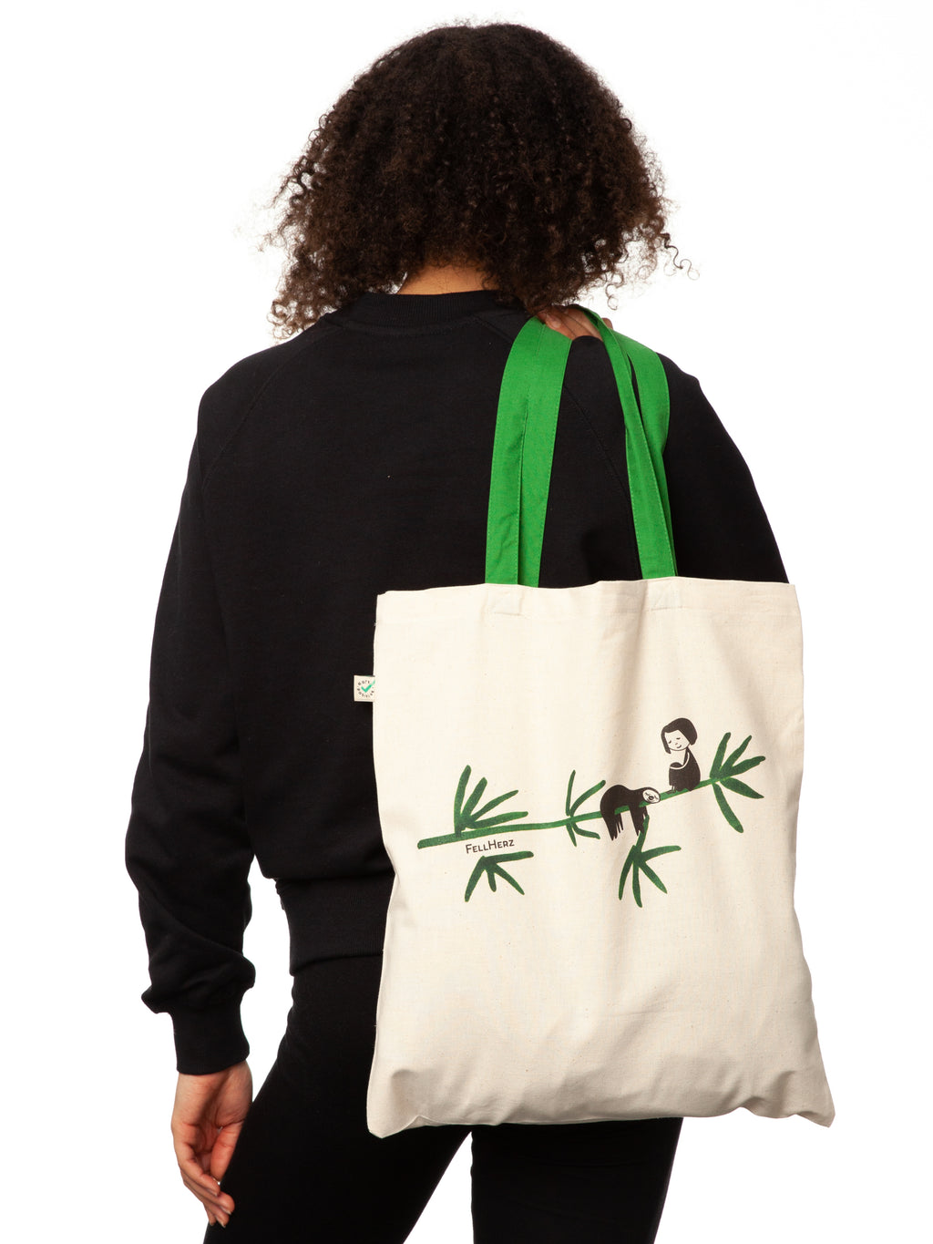 Tasche aus hochwertiger Bio-Baumwolle in Naturweiß mit grünen Henkeln mit einzigartigen FellHerz Faultier-Design in Grün auf der Vorderseite. Die liebevolle Illustration zeigt ein entspanntes Faultier, das sich an einem Zweig festhält, während ein kleines Mädchen daneben sitzt. Diese nachhaltige Bag ist ideal für umweltbewusste Modefans und Fair Fashion Liebhaberinnen und ist ein tolles Accessoire.