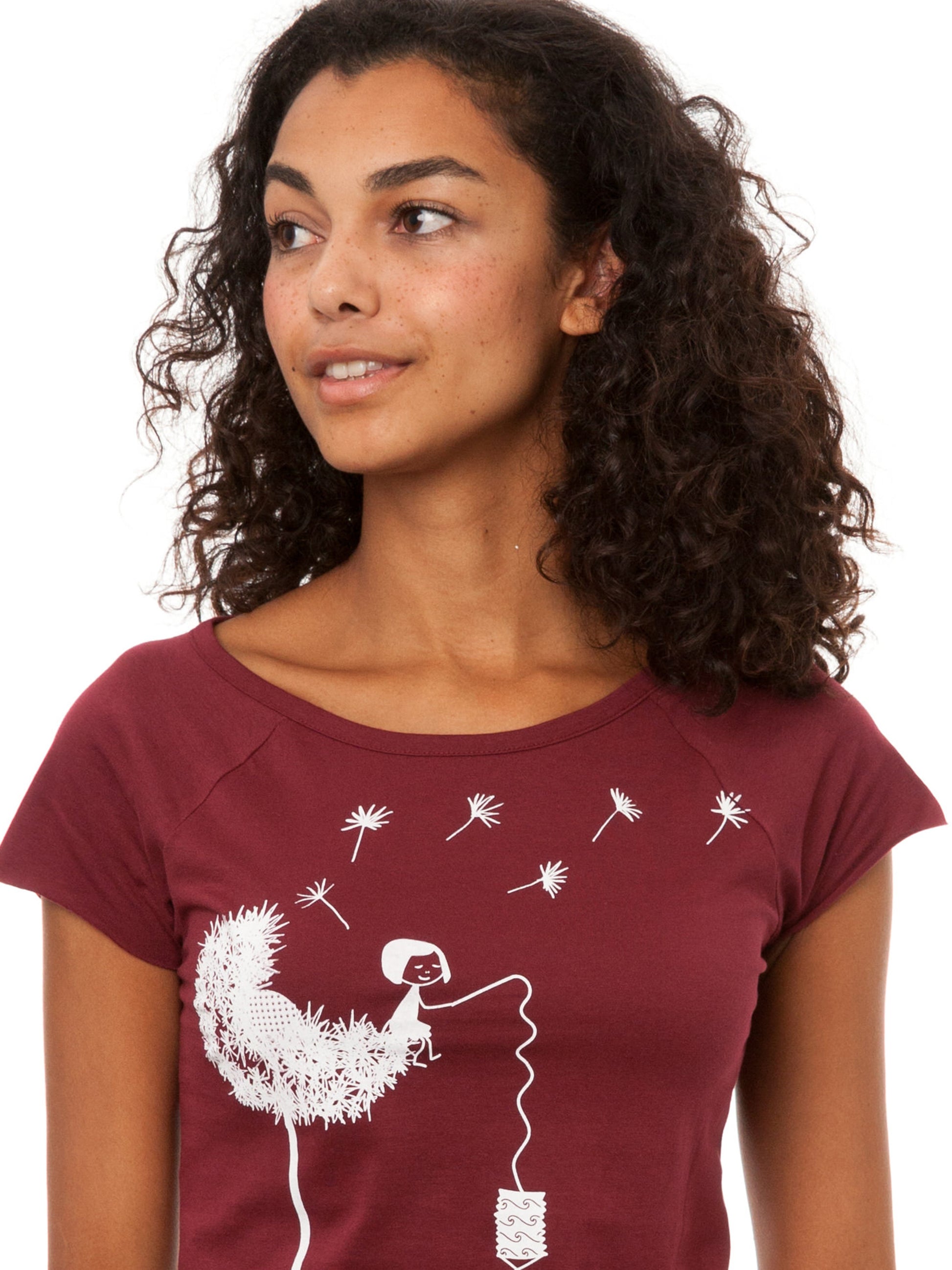Das Damen T-Shirt in tiefem Bordeauxrot besticht durch sein kreatives, weißes FellHerz-Pusteblumen-Print-Design auf der Vorderseite. Die Illustration zeigt ein Mädchen, das mit einer Laterne auf der Blume sitzt. Pusteblumen Samen fliegen davon. Das leicht taillierte Shirt hat kurze Cap-Sleeves, einen weiten Rundhalsausschnitt, besteht aus weicher, nachhaltiger Bio-Baumwolle und ist fair und vegan produziert. 