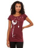 Das Damen T-Shirt in tiefem Bordeauxrot besticht durch sein kreatives, weißes FellHerz-Pusteblumen-Print-Design auf der Vorderseite. Die Illustration zeigt ein Mädchen, das mit einer Laterne auf der Blume sitzt. Pusteblumen Samen fliegen davon. Das leicht taillierte Shirt hat kurze Cap-Sleeves, einen weiten Rundhalsausschnitt, besteht aus weicher, nachhaltiger Bio-Baumwolle und ist fair und vegan produziert. 